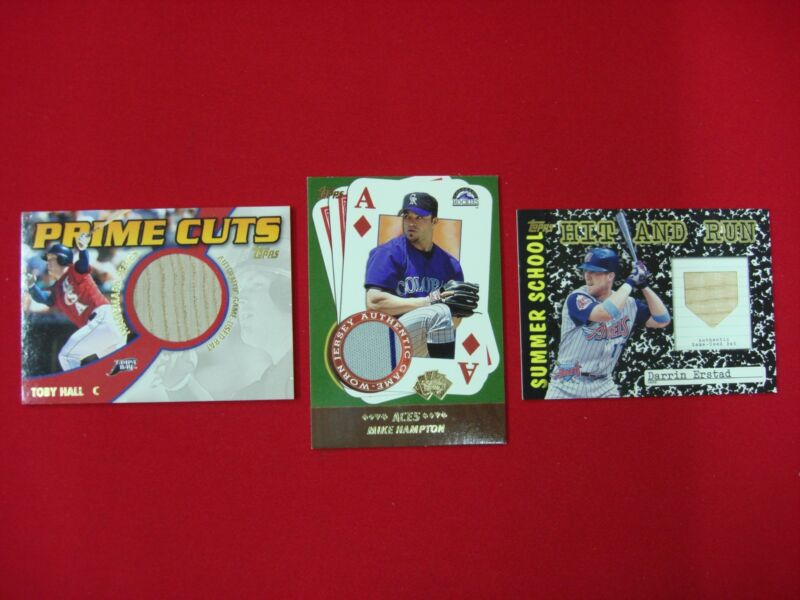 Three Topps Game Used and Worn Memorabilia baseball cards featuring Darrin Erstad, Toby Hall, and Mike Hampton.