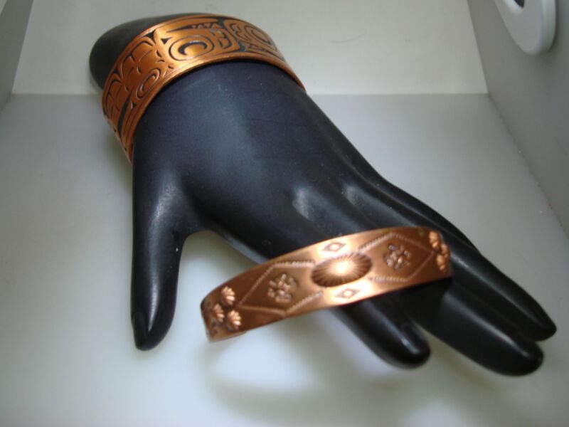Pair of vintage solid copper Southwestern cuff bracelets featuring Aztec and Native American designs.