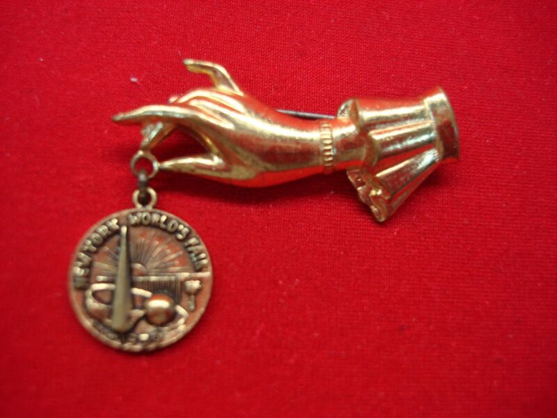 Vintage 1939 New York World's Fair pin featuring a lady's hand with the NYWF emblem.