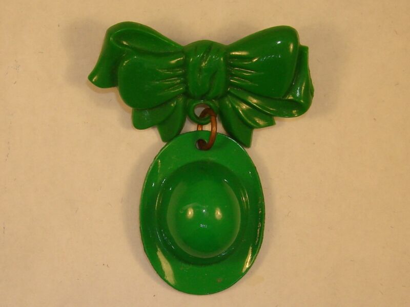Vintage green celluloid St. Patrick's Day dangle pin with a hat and bow