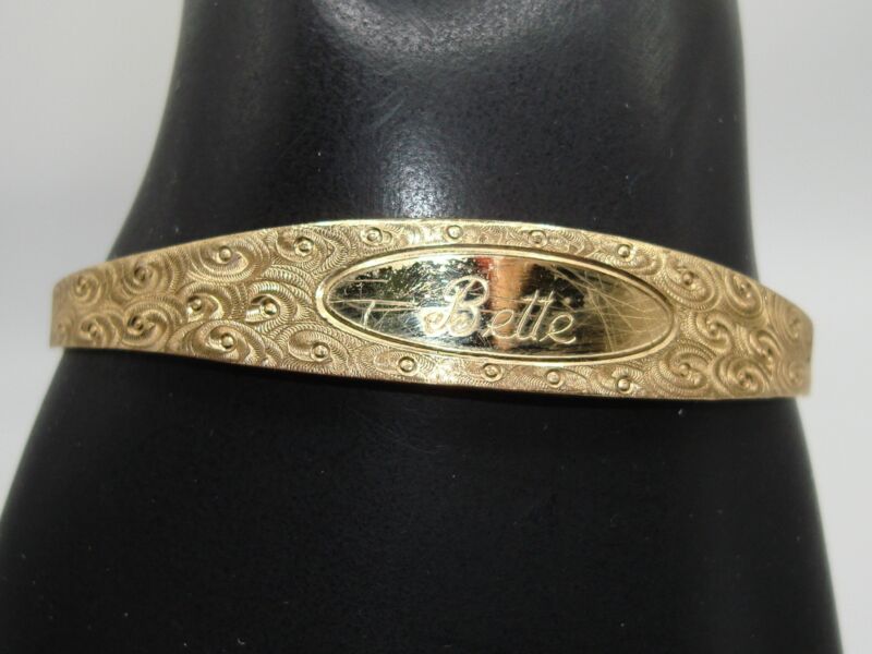 Vintage gold-tone cuff bracelet engraved 'Bette' with a heart charm.