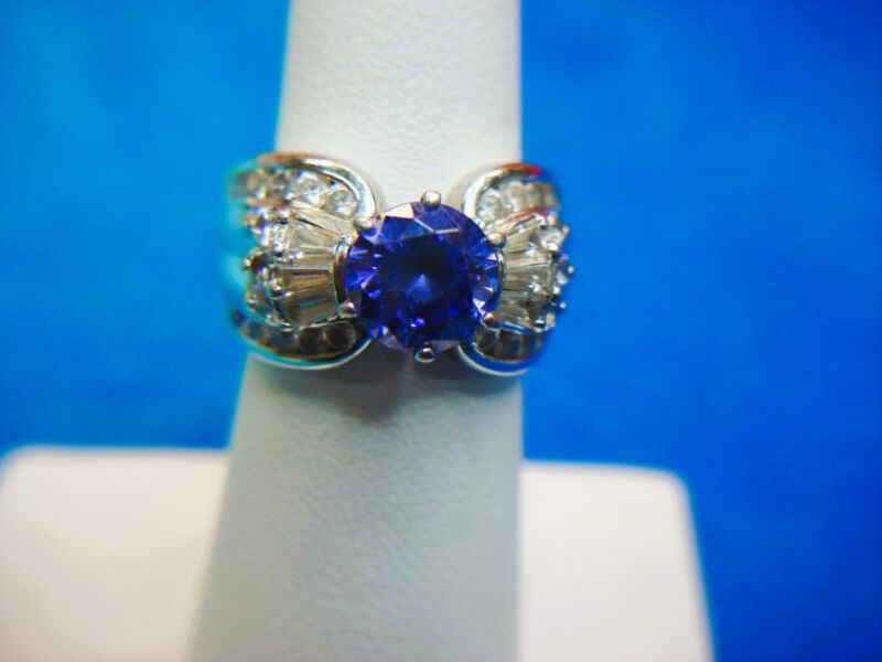 Elegant sterling silver ring with blue center stone and side CZ accents, size 6