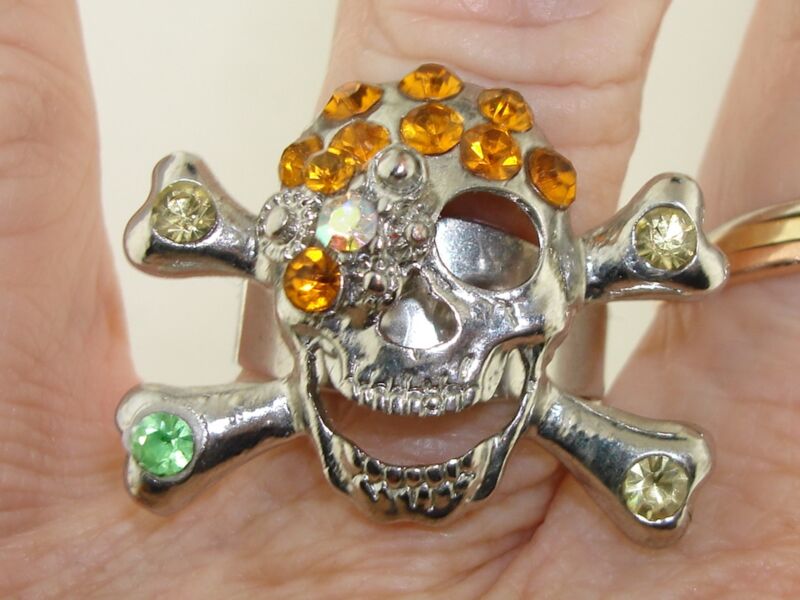 Vintage 1970s skull and crossbones ring with adjustable silver band and colorful rhinestones