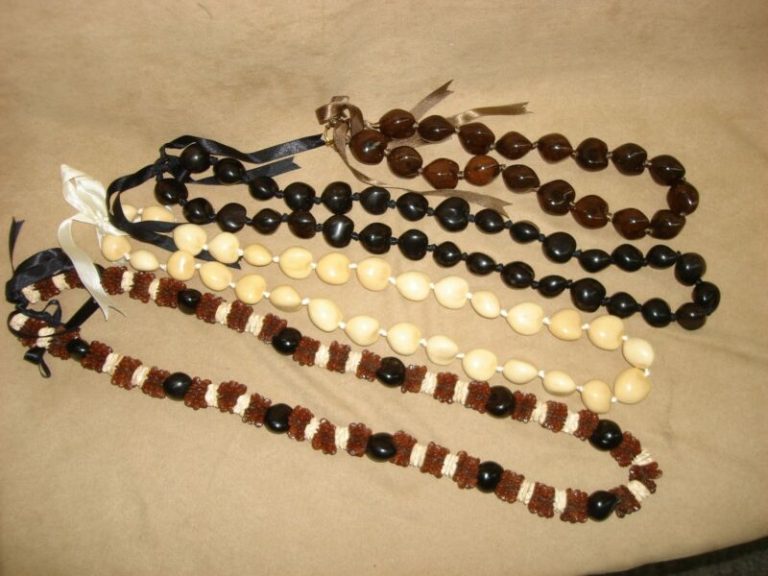 Set of four vintage Hawaiian leis featuring kukui nuts, cowrie shells, and hibiscus blossoms.