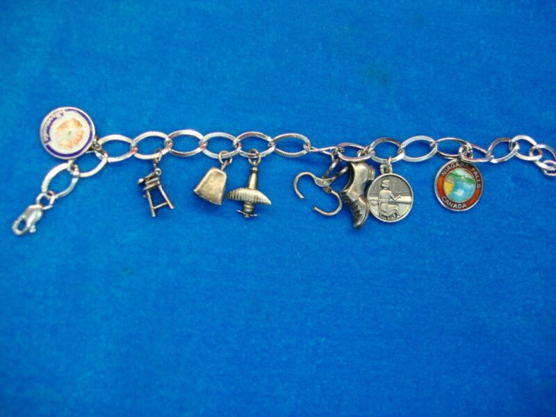Vintage sterling silver charm bracelet with eight intricately crafted charms featuring moving parts and enamel detail.