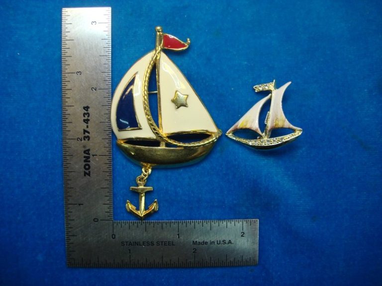 Two nautical sailboat enamel pins, one larger than the other.