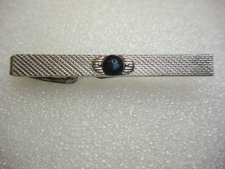 Vintage silver-tone tie clip with intricate pattern and dark blue stone