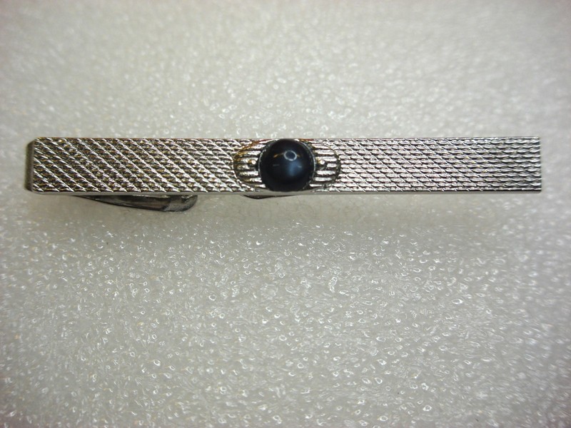 Vintage silver-tone tie clip with intricate pattern and dark blue stone