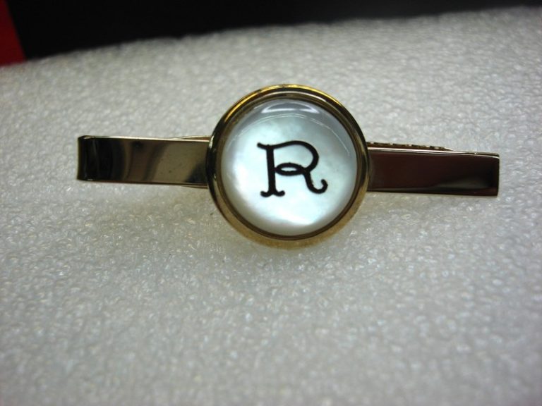 Vintage gold-tone tie clip with pearlescent 'R' design