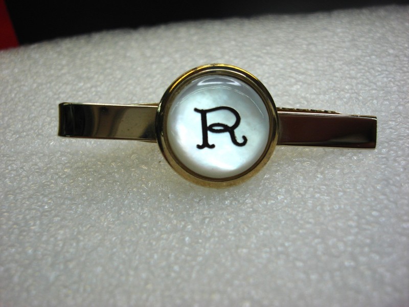 Vintage gold-tone tie clip with pearlescent 'R' design