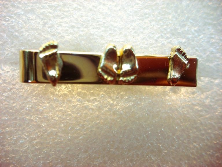 Vintage gold-tone tie clip with a playful 'naughty feet' design.