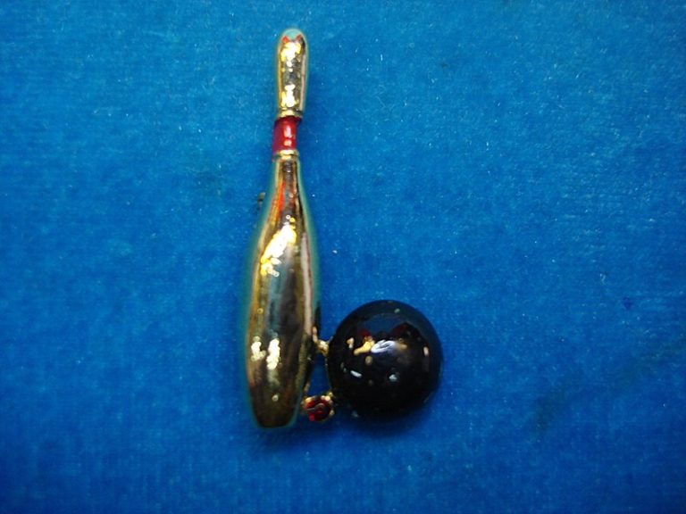 Vintage bowling pin with gold and red enamel, featuring a black ball accent and a red stone