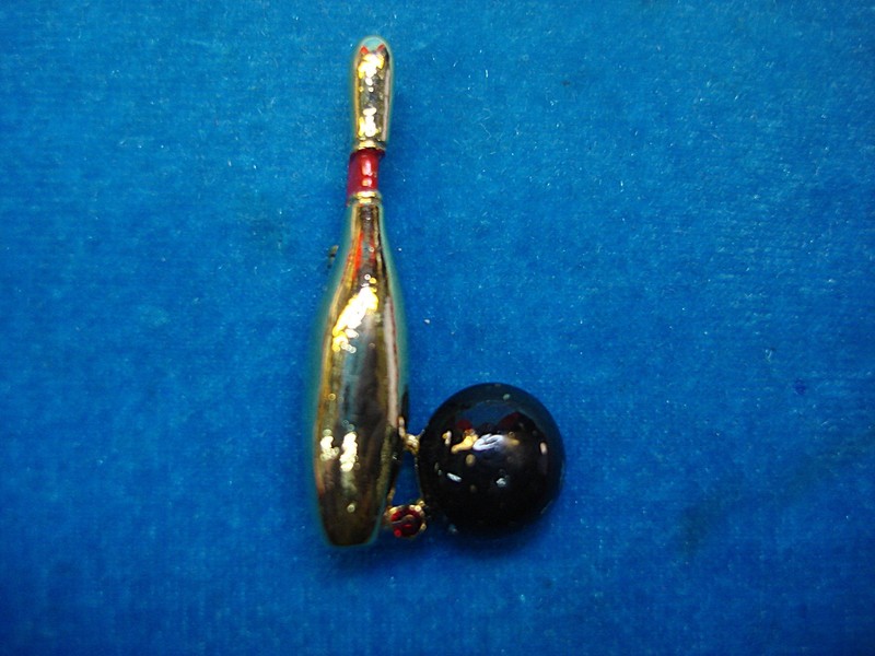 Vintage bowling pin with gold and red enamel, featuring a black ball accent and a red stone