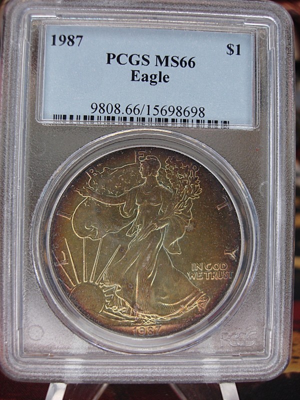 1987 Silver Eagle coin graded MS66 with gold and blue toning