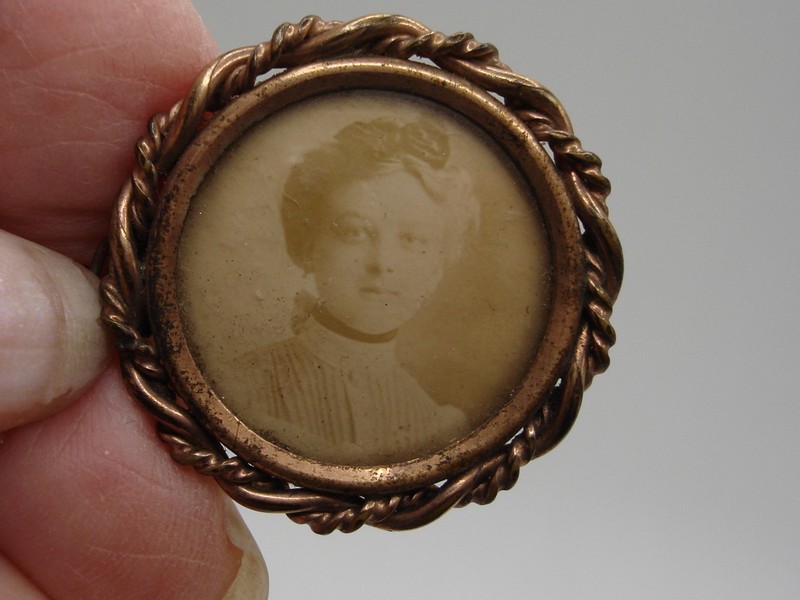 Antique rose gold photo locket brooch with braided rope border and hinged clasp.