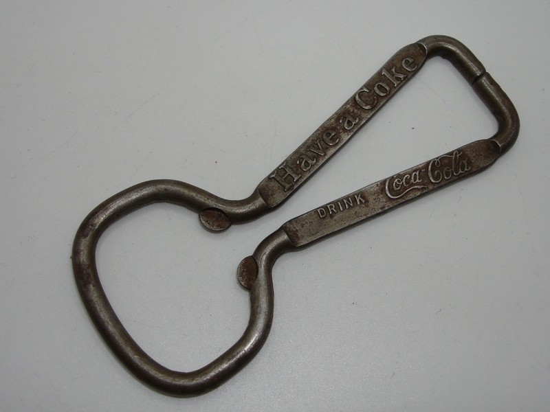 Vintage silver metal Coca-Cola bottle opener with 'Have a Coke' and 'Drink Coca-Cola' slogans.