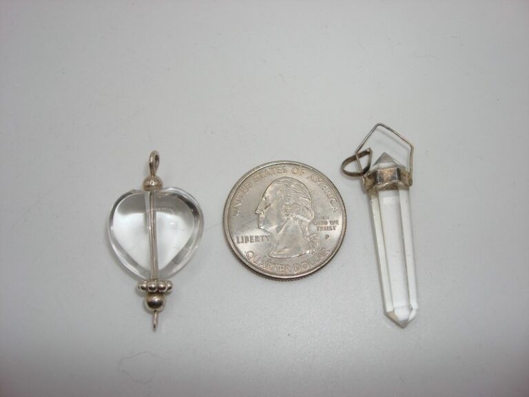 Two silver rock crystal quartz pendulums, one heart-shaped and one larger oval.