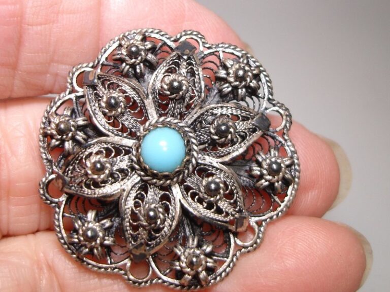 Antique silver filigree brooch or pendant with a turquoise cabochon and floral design.