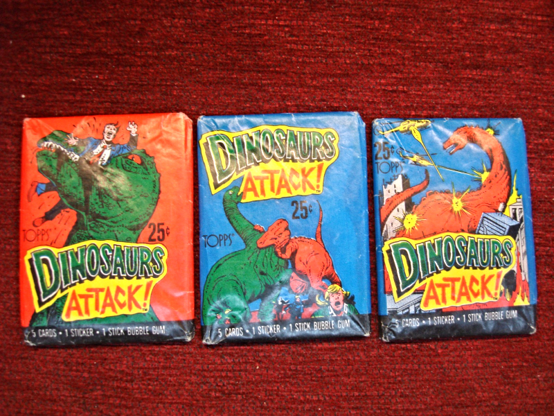 3 unopened packs of 1988 Topps Dinosaurs Attack trading cards, each with a unique cover design.