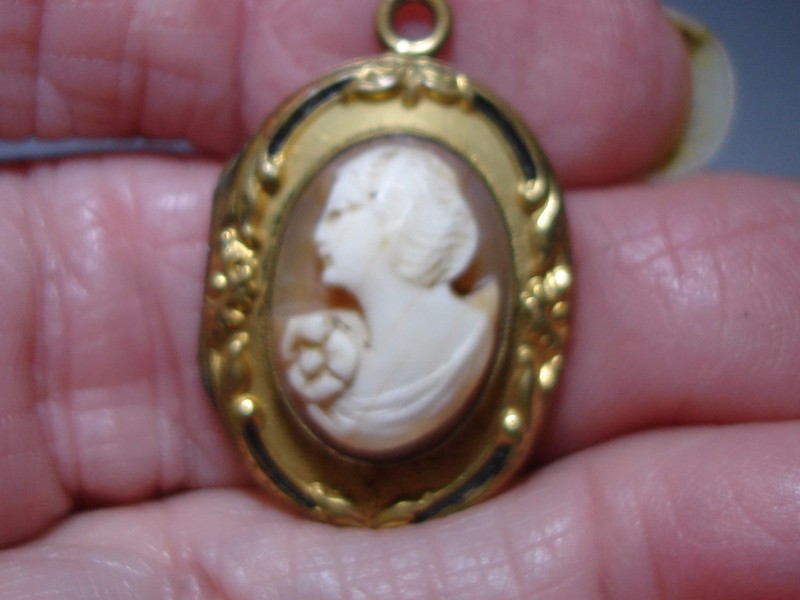 Antique Art Nouveau locket by F.M. Co. featuring a carved shell cameo of a young woman and black enamel accents.