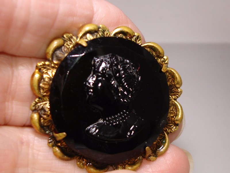 Antique Victorian cameo pin with black glass cameo of a woman in detailed attire.