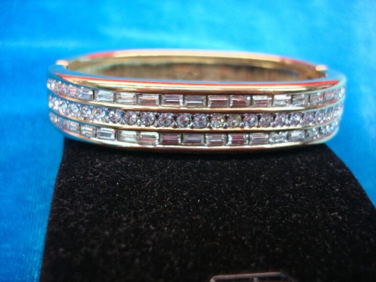 Gold-tone hinged bangle bracelet with sparkling cubic zirconia stones, signed S.A.L.