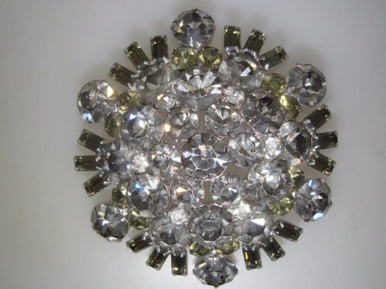 Vintage 1960s rhinestone brooch pin, 3 inches across, featuring clear and smoky gray foiled rhinestones in round and emerald cut shapes.