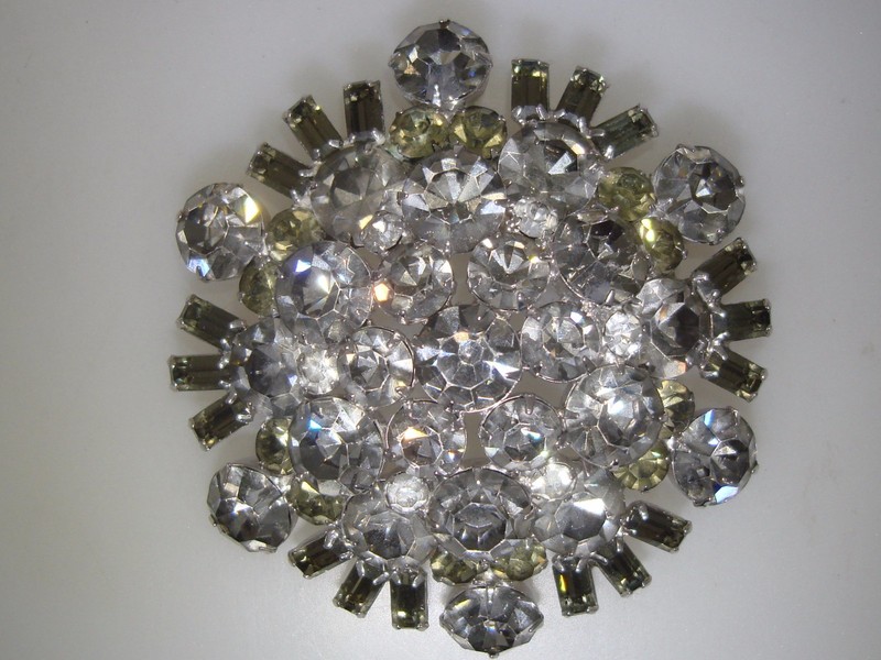 Vintage 1960s rhinestone brooch pin, 3 inches across, featuring clear and smoky gray foiled rhinestones in round and emerald cut shapes.