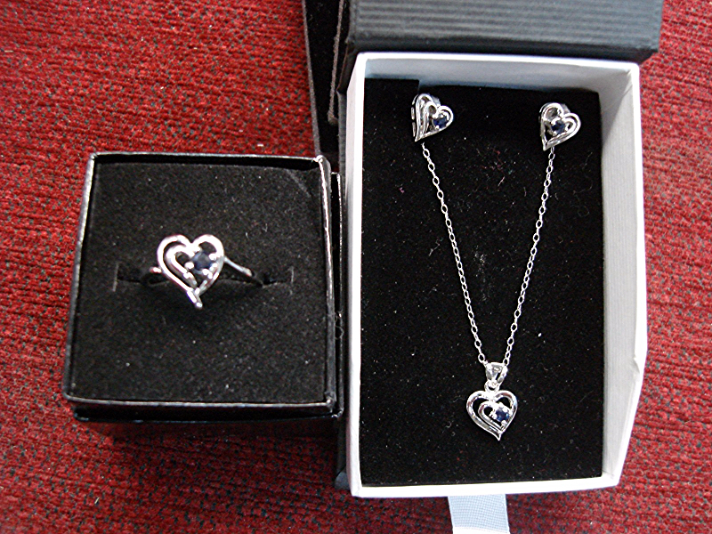 Sterling silver heart jewelry set with sapphires, includes pendant, earrings, and ring.