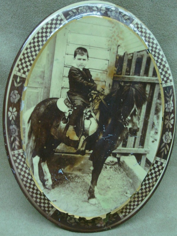 Antique oval tin picture frame with a sepia-toned photograph of a boy riding a pony.
