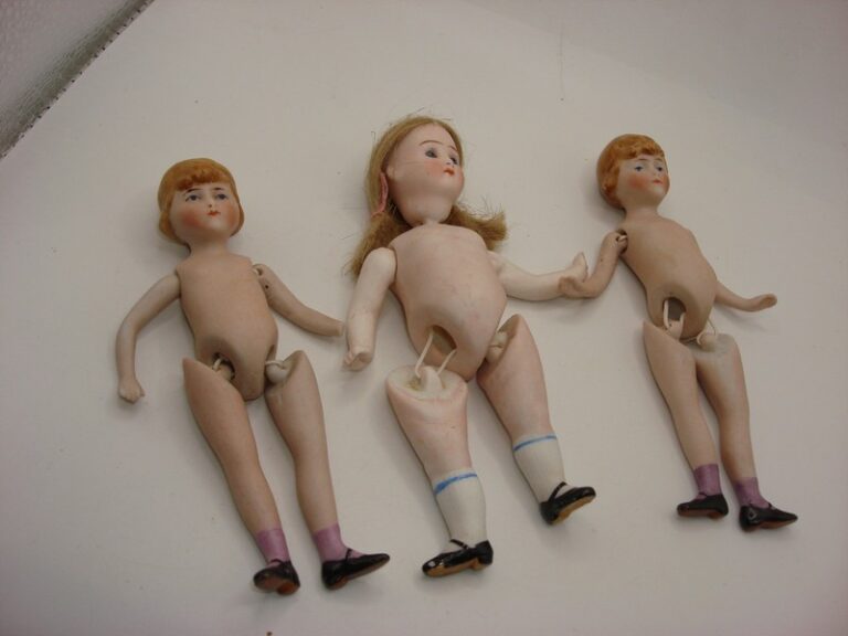 Set of three vintage German bisque dolls, including two marked '146 GERMANY' with molded hair and jointed limbs, and one unmarked doll with mohair wig and blue glass eyes.