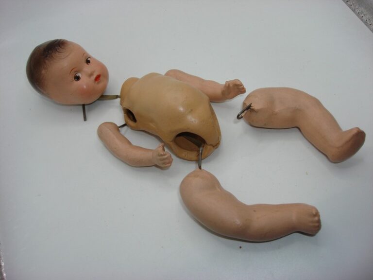 Antique composition jointed babydoll with molded brown hair and metal hardware, 7.5 inches tall